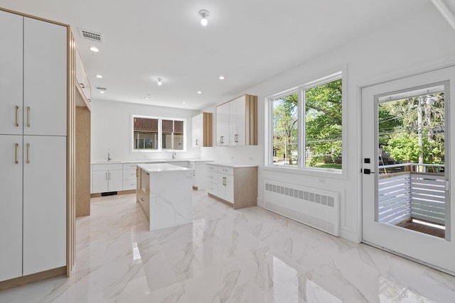 kitchen with radiator, modern cabinets, a sink, white cabinets, and recessed lighting