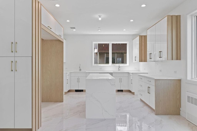 kitchen with a kitchen island, radiator heating unit, a sink, light marble finish floors, and recessed lighting
