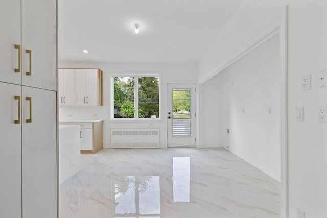 spare room with radiator heating unit and light marble finish floors