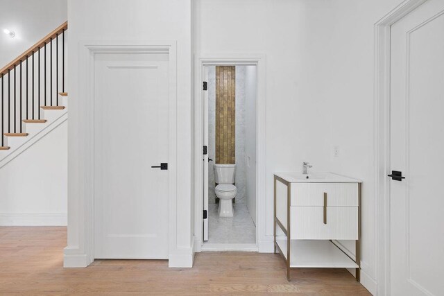 full bath featuring wood finished floors, baseboards, toilet, and a sink