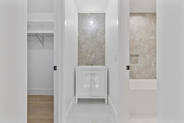 bathroom featuring wallpapered walls, baseboards, marble finish flooring, and a spacious closet