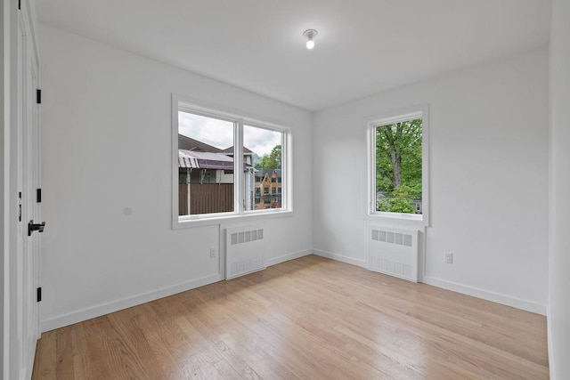 spare room featuring radiator, light wood finished floors, and healthy amount of natural light