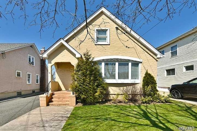 view of front of home featuring stucco siding and a front yard