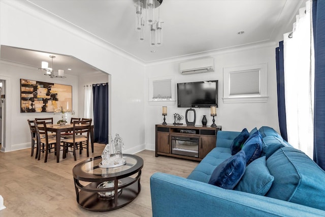 living room with a wall mounted air conditioner, light wood-style flooring, and baseboards