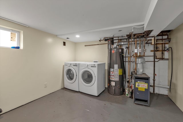 clothes washing area featuring gas water heater, washer and clothes dryer, and a heating unit