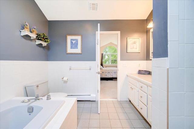 7 Cambridge Cir, Monroe, NY 10950 - ensuite bathroom featuring tile walls, a bath, tile patterned floors, baseboard heating, and a wainscoted wall