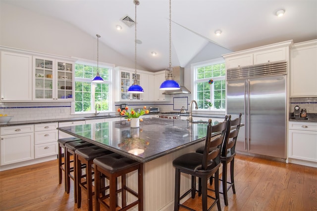 953 Peace St, Pelham, NY 10803 - kitchen with stainless steel built in refrigerator, tasteful backsplash, vaulted ceiling, a center island with sink, and glass insert cabinets