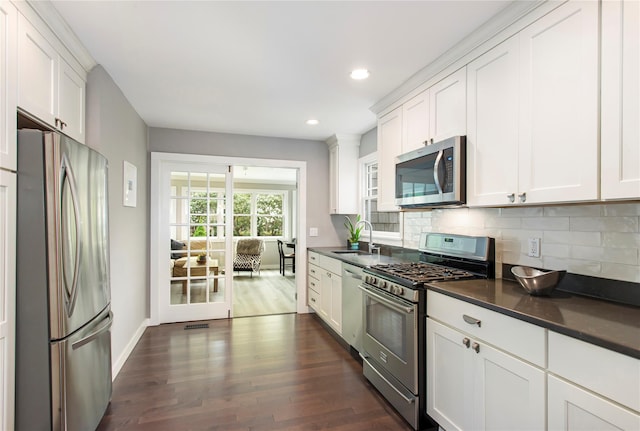 493 Water Mill Towd Rd, Southampton, NY 11968 - kitchen featuring appliances with stainless steel finishes, dark countertops, decorative backsplash, dark wood-style flooring, and white cabinetry