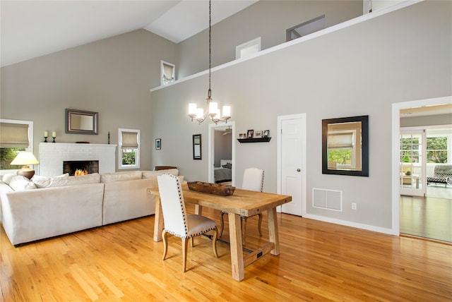 493 Water Mill Towd Rd, Southampton, NY 11968 - dining room with high vaulted ceiling, light wood-type flooring, a chandelier, baseboards, and a lit fireplace