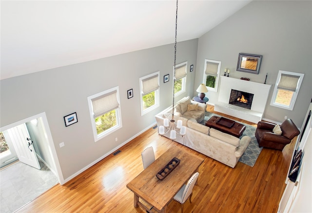 493 Water Mill Towd Rd, Southampton, NY 11968 - living room featuring high vaulted ceiling, baseboards, a lit fireplace, and light wood-type flooring