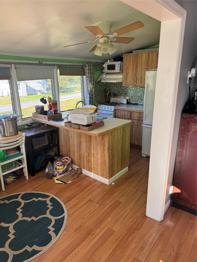 kitchen featuring white appliances, brown cabinets, a ceiling fan, under cabinet range hood, and light wood-type flooring