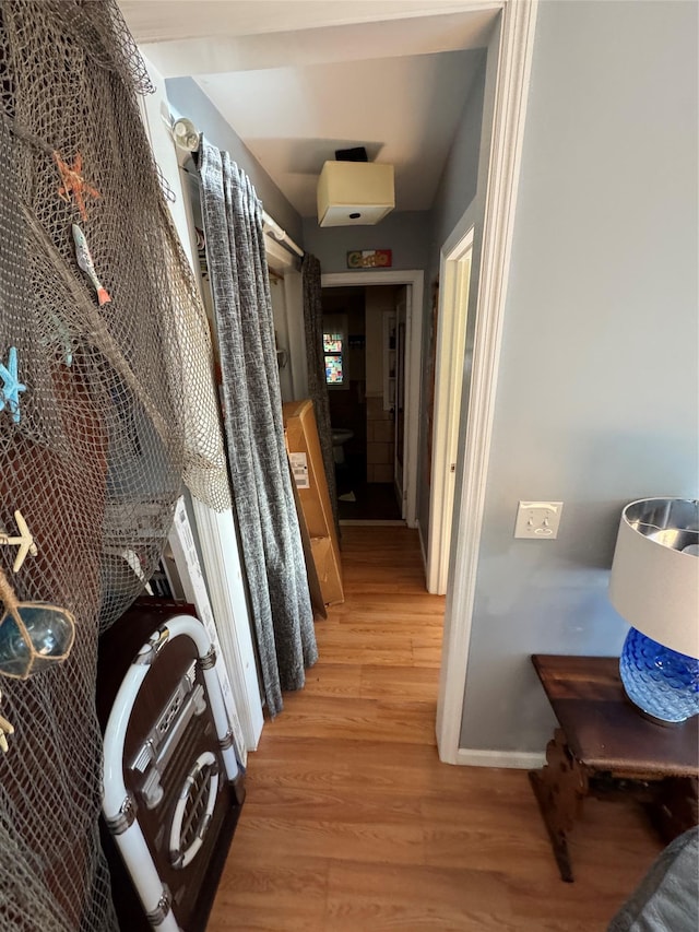 corridor featuring light wood-type flooring and baseboards