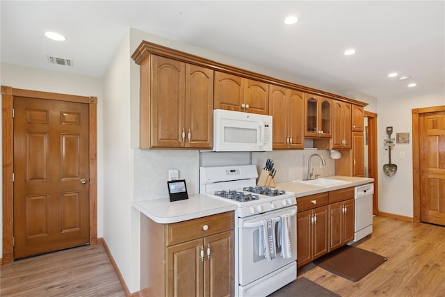 kitchen with white appliances, a sink, baseboards, light wood-style flooring, and recessed lighting