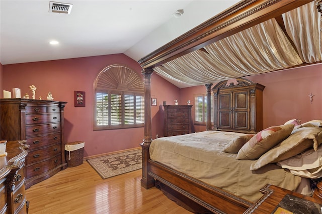 bedroom with vaulted ceiling, light wood-type flooring, and baseboards