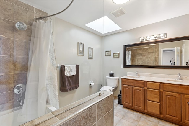 bathroom featuring a skylight, tiled shower / bath, tile patterned flooring, toilet, and double vanity