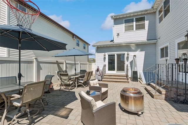view of patio featuring outdoor dining space, an outdoor fire pit, fence, and entry steps