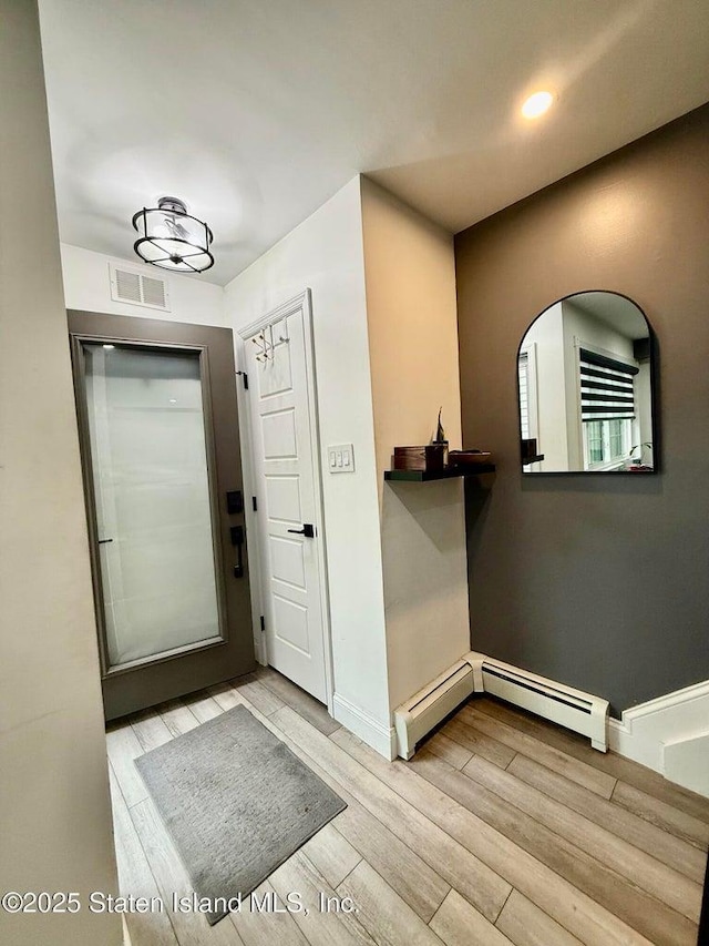 foyer entrance with wood finished floors, baseboard heating, recessed lighting, and baseboards
