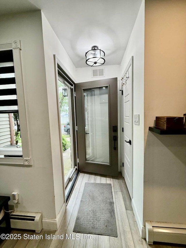 doorway to outside featuring baseboard heating, wood finished floors, and baseboards