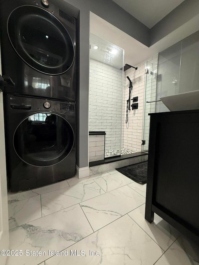 full bath with estacked washer and dryer, marble finish floors, and a walk in shower