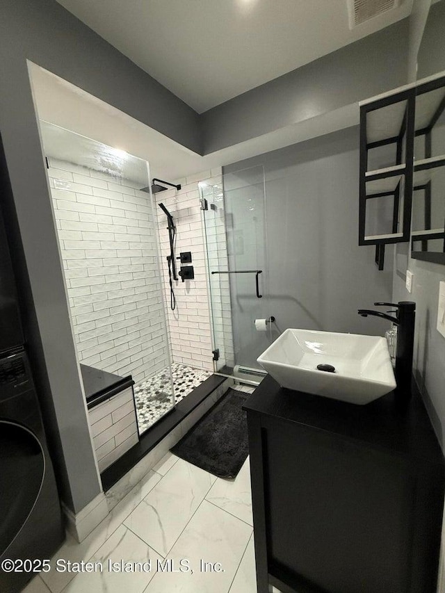 full bath with washer / dryer, a stall shower, vanity, and marble look tiles