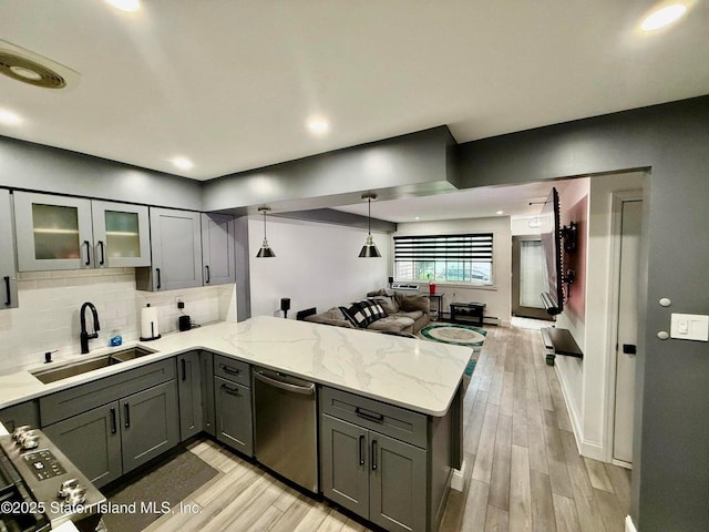 kitchen featuring a sink, stainless steel dishwasher, a peninsula, light wood-style flooring, and gray cabinets