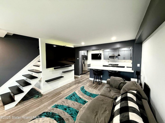 living area with light wood-style flooring, stairway, baseboards, and recessed lighting