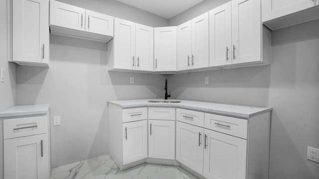 455 E 40th St, Brooklyn, NY 11203 - kitchen with a sink, light marble finish flooring, white cabinets, and baseboards
