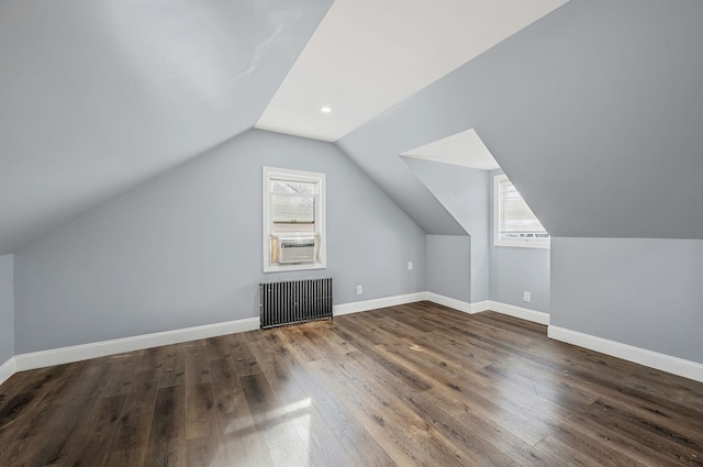 bonus room featuring radiator, healthy amount of natural light, wood finished floors, vaulted ceiling, and baseboards