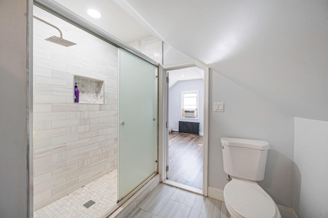full bath with a stall shower, toilet, vaulted ceiling, and baseboards