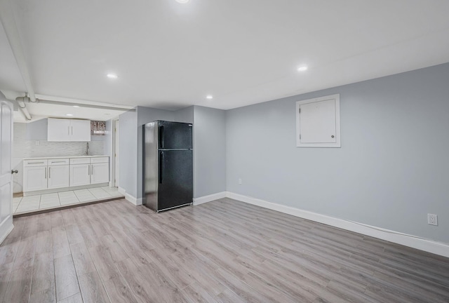 unfurnished living room featuring light wood-type flooring, recessed lighting, baseboards, and a sink