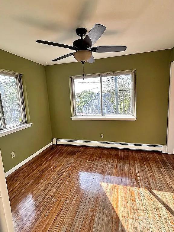 102 Maple St, Croton-On-Hudson, NY 10520 - spare room featuring wood finished floors, a ceiling fan, baseboards, and a baseboard heating unit