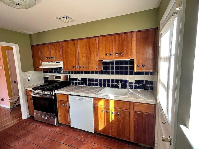 102 Maple St, Croton-On-Hudson, NY 10520 - kitchen featuring gas stove, white dishwasher, under cabinet range hood, tile counters, and a sink