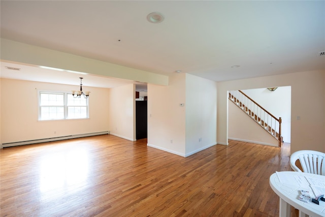 21 Pine Cone St, Middle Island, NY 11953 - spare room with a baseboard radiator, a chandelier, wood finished floors, baseboards, and stairs