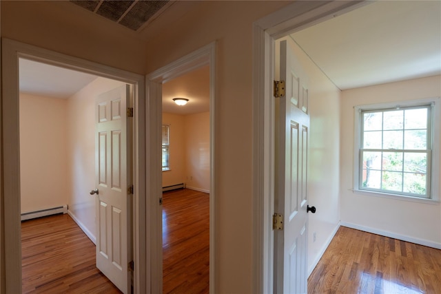 21 Pine Cone St, Middle Island, NY 11953 - hall featuring a baseboard heating unit, wood finished floors, baseboards, and a baseboard radiator