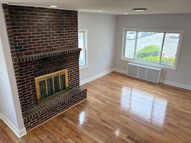 187-02 Foch Blvd, Saint Albans, NY 11412 - unfurnished living room with radiator, baseboards, wood finished floors, a fireplace, and recessed lighting