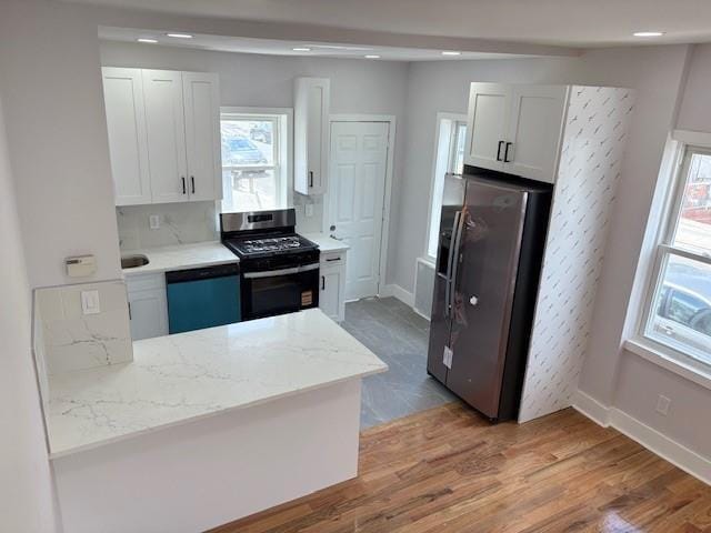 187-02 Foch Blvd, Saint Albans, NY 11412 - kitchen featuring appliances with stainless steel finishes, white cabinets, wood finished floors, baseboards, and light stone countertops
