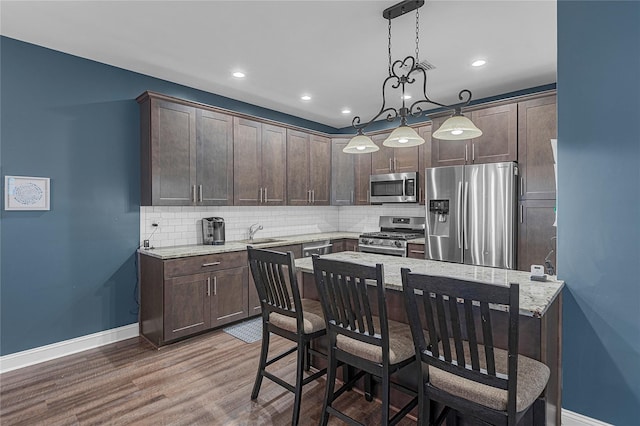 27 Lager Ln, Patchogue, NY 11772 - kitchen with appliances with stainless steel finishes, dark brown cabinets, a sink, baseboards, and backsplash