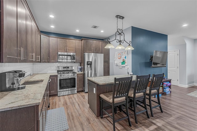 27 Lager Ln, Patchogue, NY 11772 - kitchen featuring stainless steel appliances, a sink, dark brown cabinets, a breakfast bar, and light wood-type flooring