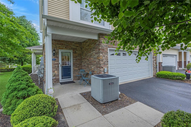 27 Lager Ln, Patchogue, NY 11772 - porch featuring cooling unit, driveway, and a garage