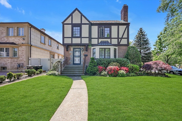 182-04 80th Dr, Jamaica Estates, NY 11432 - tudor house featuring a chimney, stucco siding, brick siding, and a gate