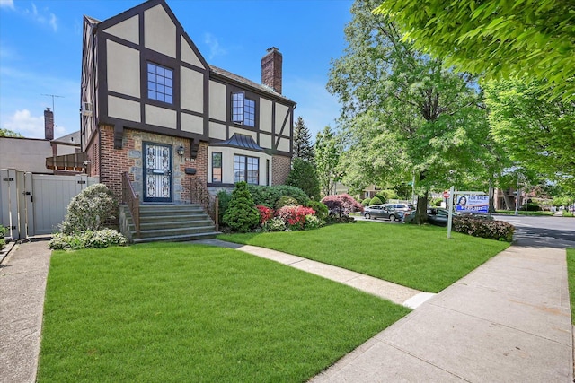 182-04 80th Dr, Jamaica Estates, NY 11432 - tudor house featuring stucco siding, brick siding, a chimney, and a gate