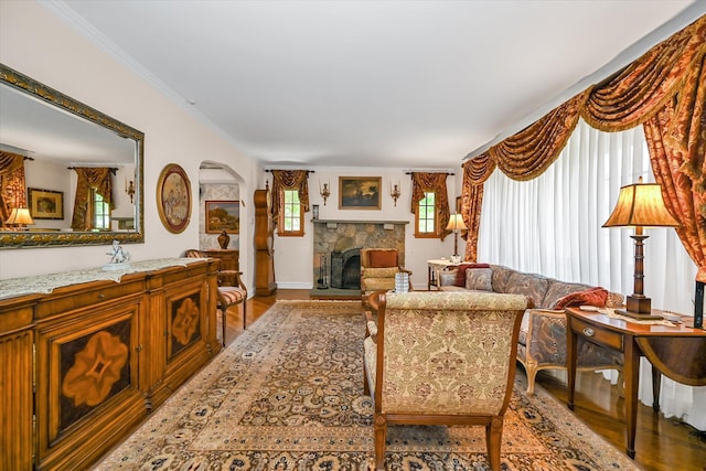182-04 80th Dr, Jamaica Estates, NY 11432 - living area featuring light wood-style flooring, a stone fireplace, baseboards, arched walkways, and crown molding