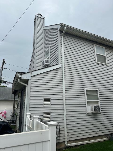 459 Monroe Blvd, Long Beach, NY 11561 - view of side of property featuring fence, a chimney, and cooling unit