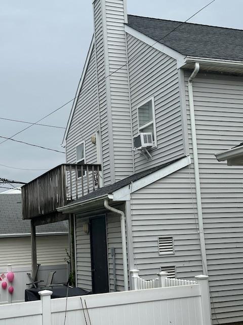 459 Monroe Blvd, Long Beach, NY 11561 - view of home's exterior featuring a balcony, fence, a chimney, and a shingled roof