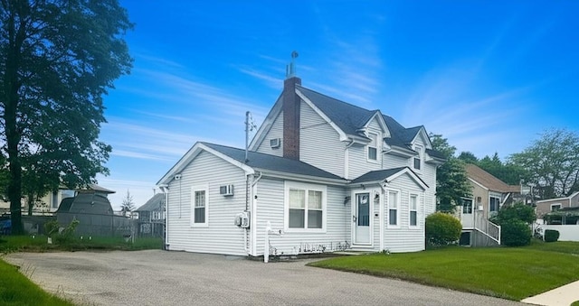 view of front of property with entry steps, a front yard, and a wall mounted air conditioner