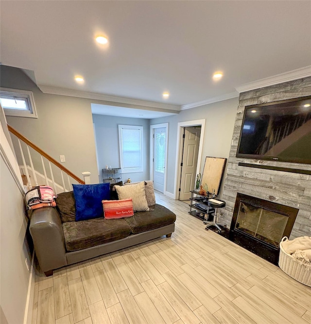 living room featuring wood finished floors, a stone fireplace, stairway, ornamental molding, and baseboards