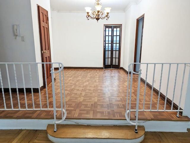 entrance foyer with a chandelier, ornamental molding, and baseboards