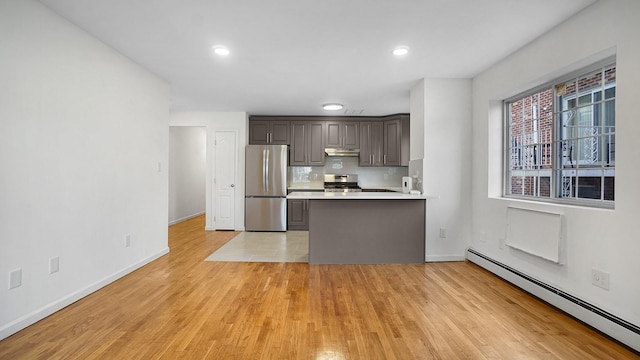 907 Clarence Ave, Bronx, NY 10465 - kitchen with stainless steel appliances, baseboard heating, under cabinet range hood, light countertops, and a peninsula