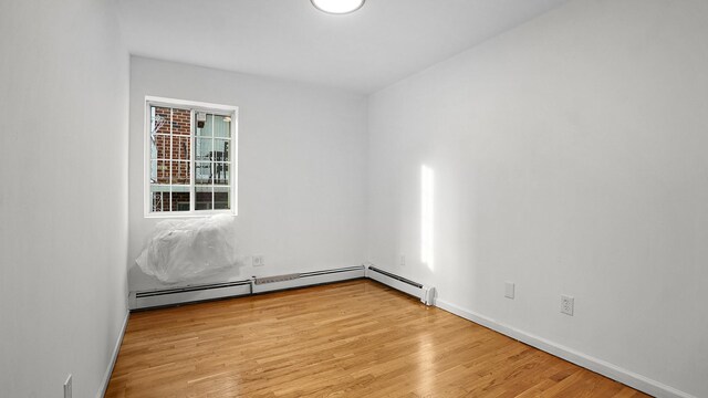 907 Clarence Ave, Bronx, NY 10465 - empty room with light wood-style floors, baseboards, and a baseboard heating unit