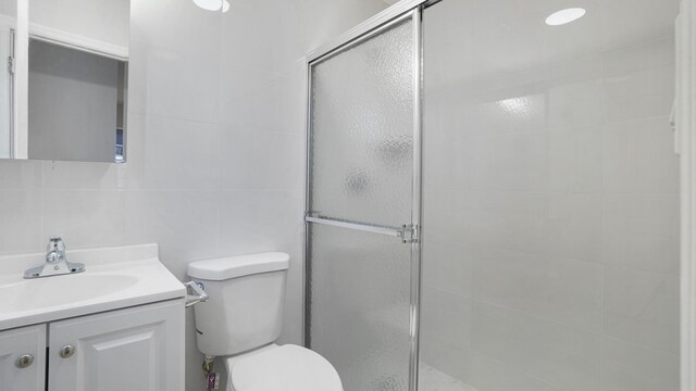 907 Clarence Ave, Bronx, NY 10465 - bathroom featuring a stall shower, tile walls, toilet, and vanity